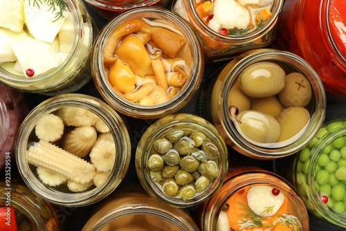 Different pickled products in jars on table, top view