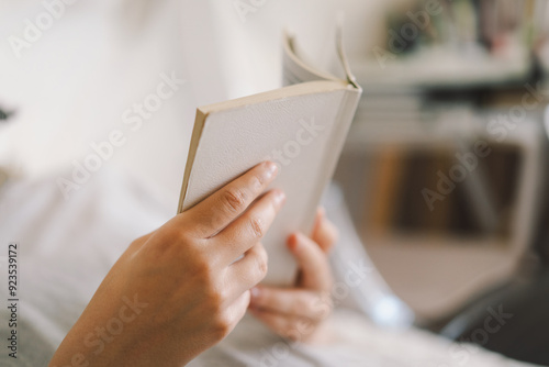 A woman relaxes on a couch, holding a mug and immersed in her reading, surrounded by a calm, inviting atmosphere.