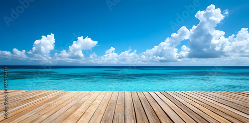 Wooden deck in front of clear blue ocean with clouds in the sky