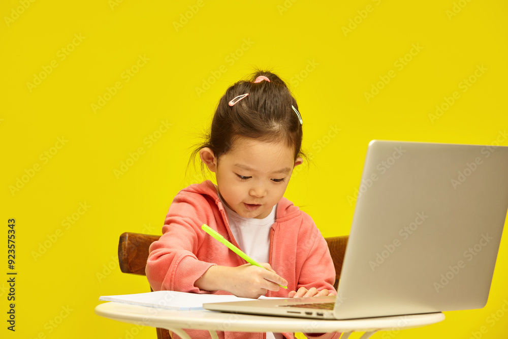 Diligent Japanese little Girl Focused on Writing Assignment. Preschool sweet kid Working on Study Task with Laptop. Diligent Japanese little Girl Focused on Writing Assignment. Preschool sweet kid Working on Study Task with Laptop.