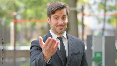 Portrait of Young Businessman inviting People Outdoor