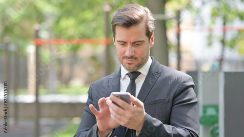 Portrait of Young Businessman Text Messaging on Phone Outdoor