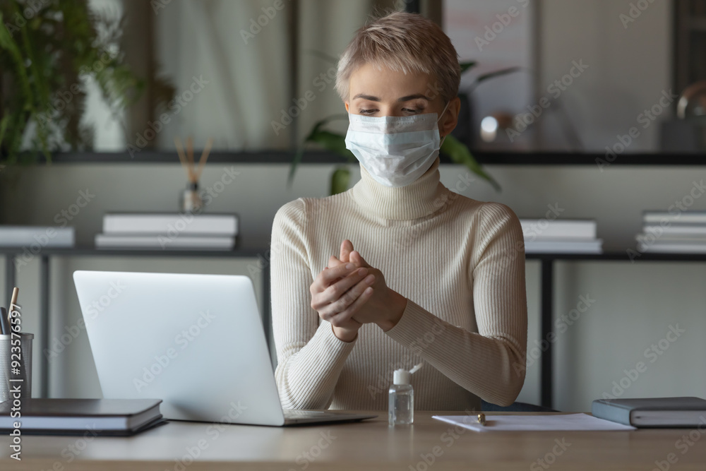 Young woman in protective face mask sit at desk cleanse hands with sanitizer protect from covid-19 pandemic, female employee disinfect with antibacterial gel, healthcare, coronavirus outbreak concept Young woman in protective face mask sit at desk cleanse hands with sanitizer protect from covid-19 pandemic, female employee disinfect with antibacterial gel, healthcare, coronavirus outbreak concept