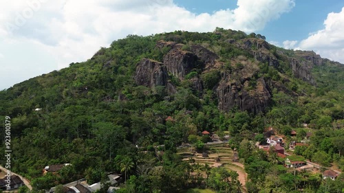 4k aerial footage of the Nglanggeran Ancient Volcano ecotourism area during the day using a drone. Aerial footage of ancient rock hills surrounded by lush trees in a beautiful rural area photo