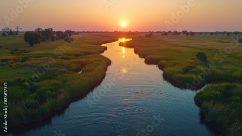 Sunset over a tranquil river winding through lush green fields in rural landscape