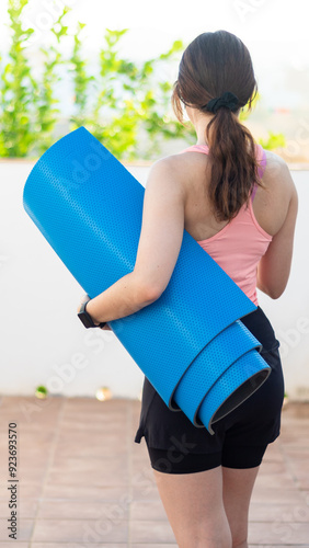 Vertical shot of a beautiful young active woman in sportswear with a yoga mat ready for a fitness session outdoors. Workout at home concept.