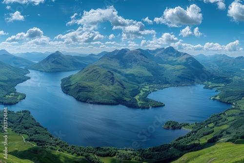 Aerial View of a Serpentine Lake Surrounded by Lush Green Mountains Under a Blue Sky