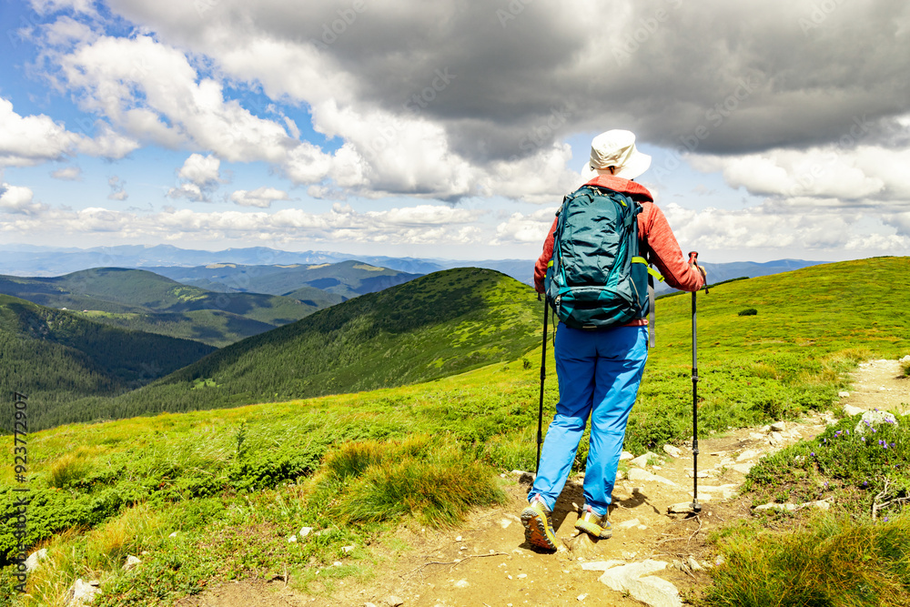 Hiking high in the mountains with a backpack and walking poles.