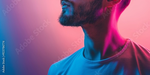 A close-up profile shot of a bearded man softly illuminated by contrasting pink and blue lights creating modern mood. photo