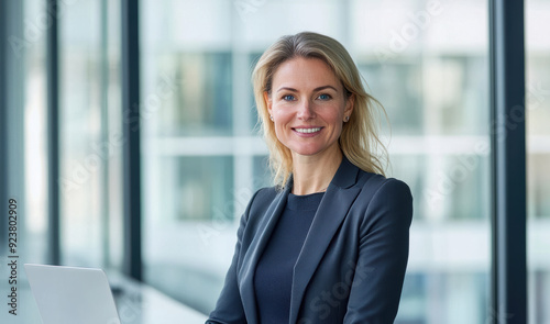 Smiling businesswoman efficiently working on her laptop in a bright  modern office.