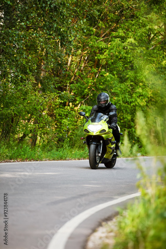 motorcyclist riding a green motorcycle on an asphalt road