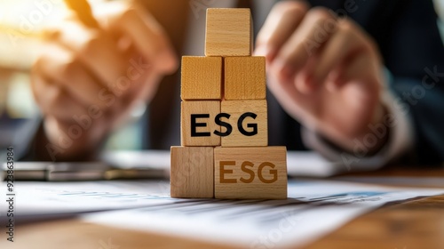 A person is building a tower of wooden blocks with the letters ESG on top