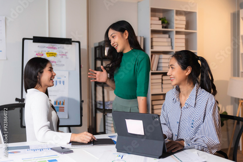 Group of smiling asian businesswomen having a discussion in the office, developing a marketing strategy for their startup company