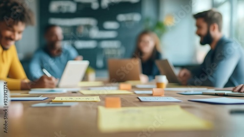 A diverse group collaborates in a modern workspace, utilizing technology and brainstorming ideas around a table filled with notes.