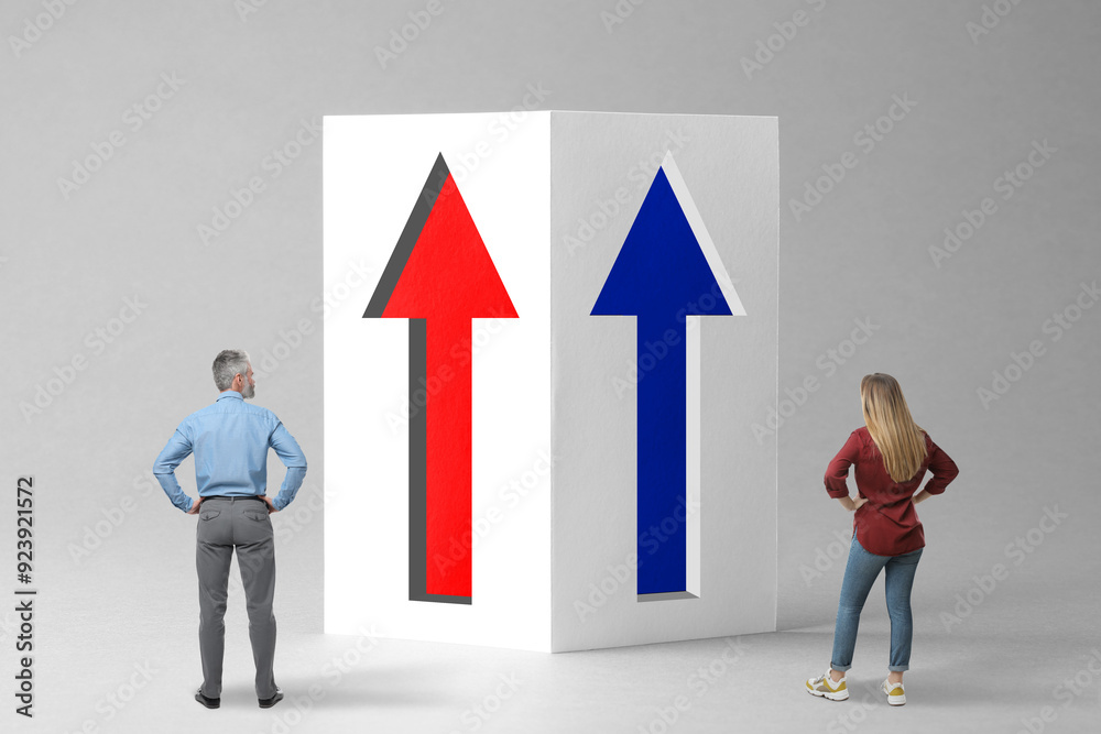 Man and woman looking at paper with arrows on grey background. Concepts of competition, gender equality Man and woman looking at paper with arrows on grey background. Concepts of competition, gender equality