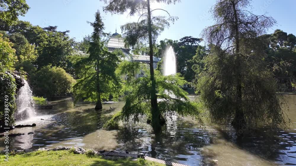 A pond with a fountain in the middle and trees surrounding it. El Retiro Park, Madrid A pond with a fountain in the middle and trees surrounding it. El Retiro Park, Madrid