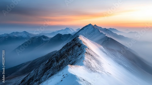 A breathtaking view of a snow-capped mountain ridge at sunrise, with a misty backdrop of undulating mountains fading into the horizon. photo