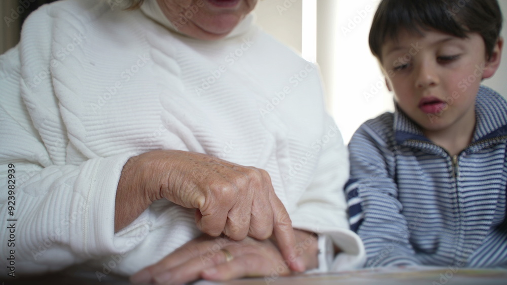 Close-up of an elderly woman's hand pointing at a book page while her grandson attentively follows along, moment of shared learning and intergenerational connection, storytelling Close-up of an elderly woman's hand pointing at a book page while her grandson attentively follows along, moment of shared learning and intergenerational connection, storytelling