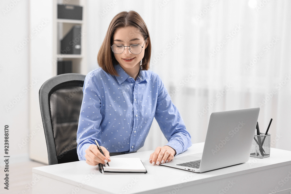 Teenager taking notes while working with laptop at home. Remote job Teenager taking notes while working with laptop at home. Remote job