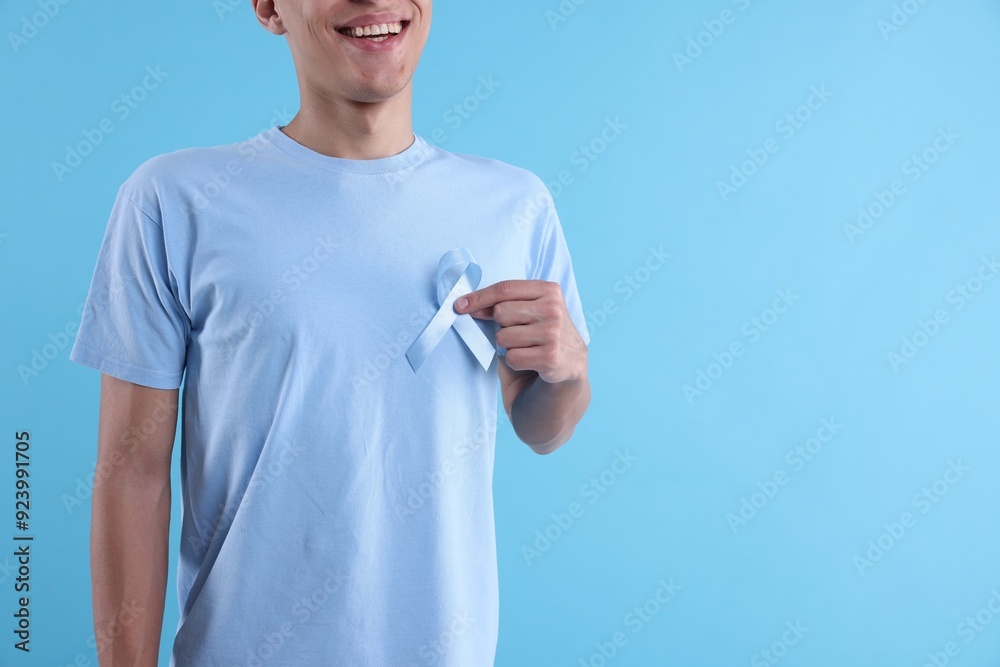 Prostate cancer awareness. Man with light blue ribbon as symbol of support on color background, closeup. Space for text Prostate cancer awareness. Man with light blue ribbon as symbol of support on color background, closeup. Space for text