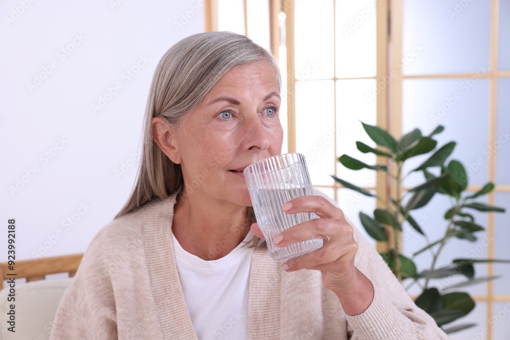 Beautiful senior woman drinking water at home