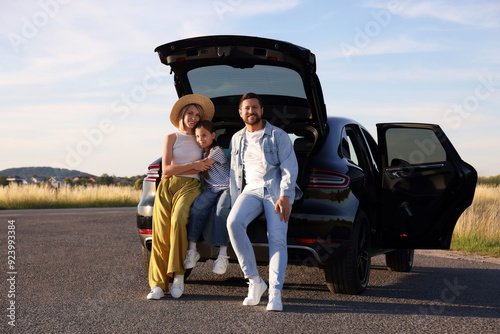 Happy family sitting in trunk of car outdoors