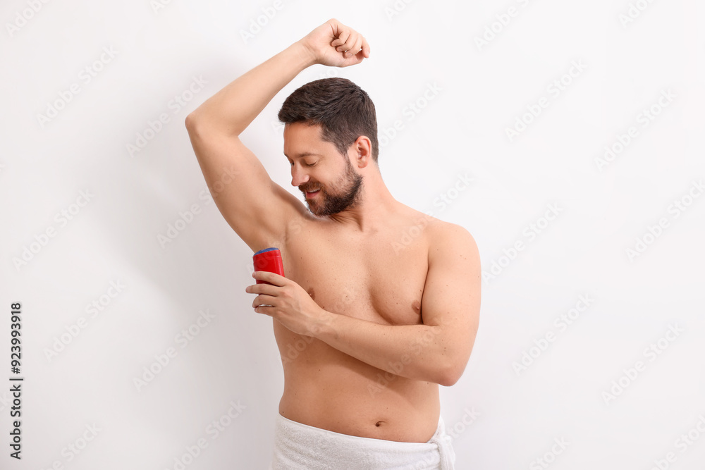 Obraz premium Handsome man applying solid deodorant on white background