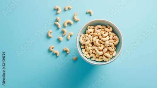 cashew nuts falling into a bowl on a blue background 