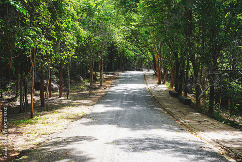 Empty curved concrete road and path way through a green nature park with trees and rocks in the forest, view in Tat Ton Waterfall at Tat Ton National Park, Chaiyaphum, Thailand. photo