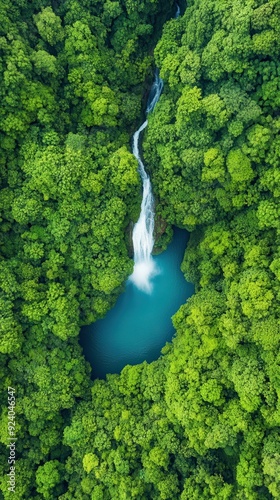 Aerial of a cascading waterfall plunging into a deep pool surrounded by lush tropical vegetation, creating a powerful and mesmerizing natural spectacle