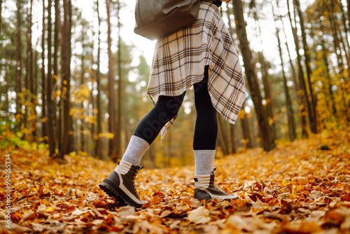 Close-up of female legs in hiking boots walking on ground with yellow-orange dry fall leaves during autumn season in park or forest. Healthy lifestyle on leisure activity. photo