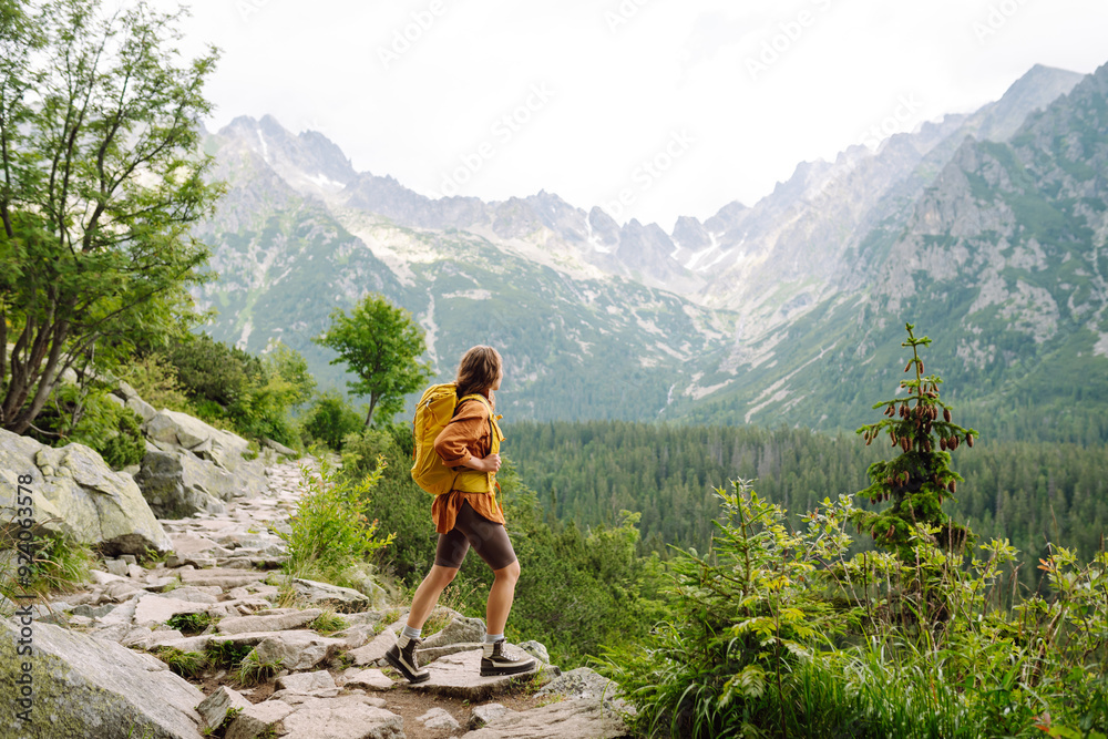 Smiling female with backpack on hike in nature. Beautiful woman hiker standing on mountain trail and looking at camera smiling. Lifestyle, adventure, nature, active life. Smiling female with backpack on hike in nature. Beautiful woman hiker standing on mountain trail and looking at camera smiling. Lifestyle, adventure, nature, active life.