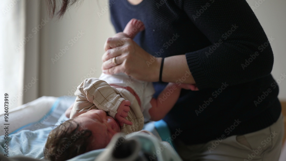 Obraz premium Mother dressing newborn baby, gently guiding arm into sleeve, emphasizing care and attention, capturing tender moments of bonding, showing love, early stages of infant care
