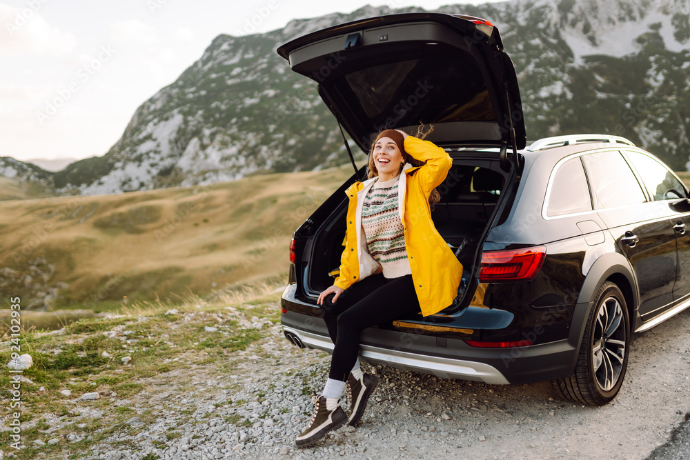 Young woman sits in the trunk of a car. Stop during a journey. The concept of traveling by car, tourism, trip, active lifestyle. Young woman sits in the trunk of a car. Stop during a journey. The concept of traveling by car, tourism, trip, active lifestyle.