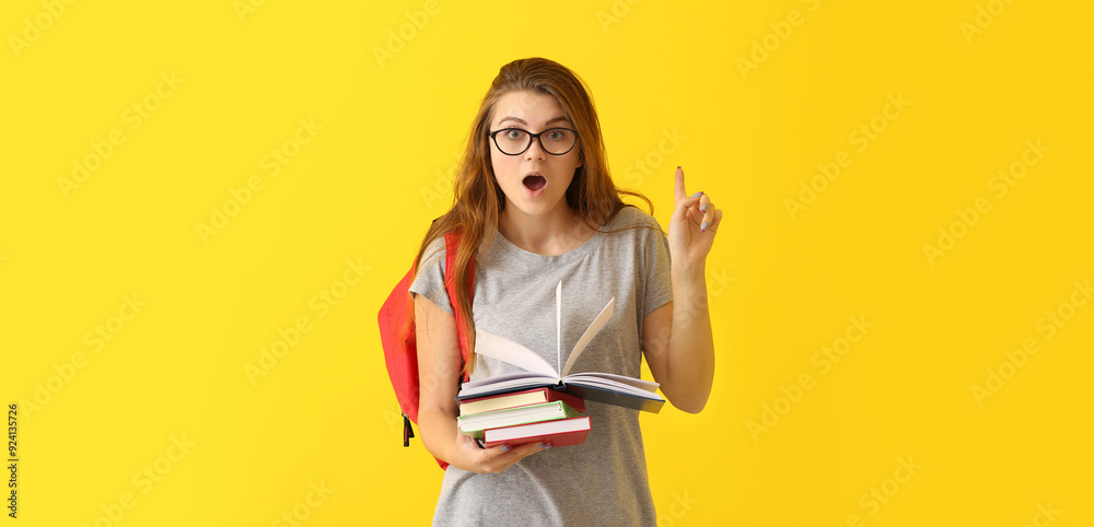 Emotional schoolgirl with books and raised index finger on color background Emotional schoolgirl with books and raised index finger on color background