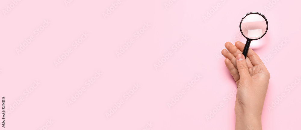 Female hand with magnifier on pink background Female hand with magnifier on pink background