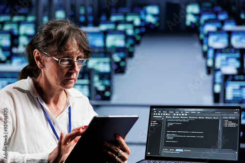 Old computer scientist writing script code in data center on laptop terminal. Adept professional doing maintenance work in server room, updating rigs software to prevent malfunctions