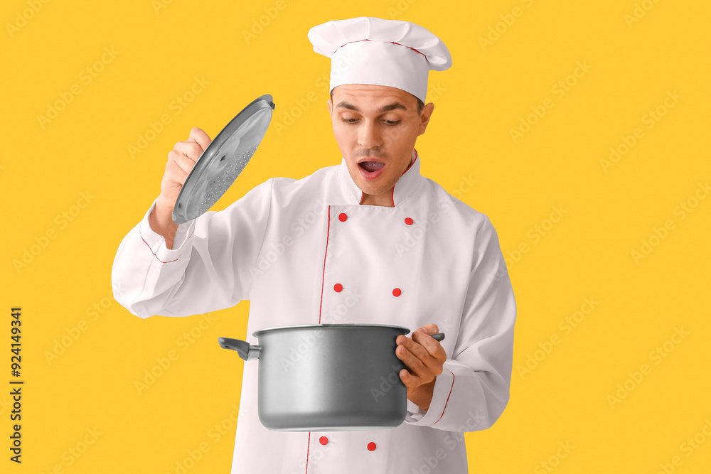 Handsome shocked male chef with cooking pot on yellow background Handsome shocked male chef with cooking pot on yellow background