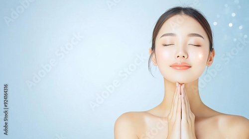 Beautiful Asian woman with flawless skin and closed eyes on blue background.