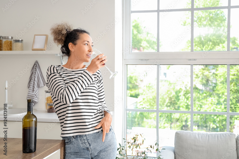 Beautiful middle-aged woman with bottle and glass of red wine at home Beautiful middle-aged woman with bottle and glass of red wine at home