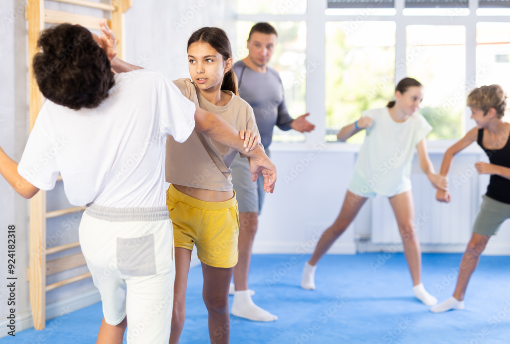 Fototapeta premium Boy and girl practicing self-defense techniques in group at gym
