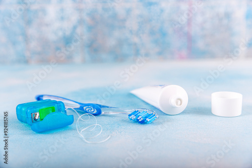 Dental floss and toothbrush on blue background. Tongue cleaner and other oral care products, dental hygiene concept. photo