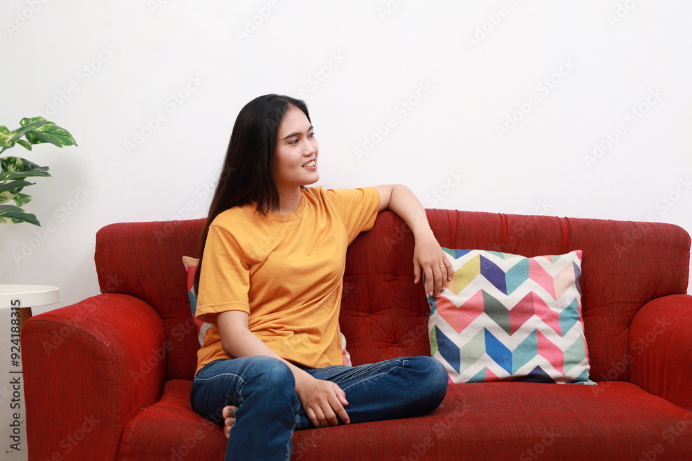 Young asian woman in casual clothes look aside sits on sofa couch stay at home flat rest relax spend free spare time in living room indoor Young asian woman in casual clothes look aside sits on sofa couch stay at home flat rest relax spend free spare time in living room indoor