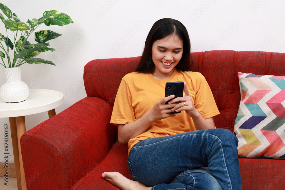 Happy young asian woman relax on comfortable couch at home texting messaging on smartphone, smiling girl use cellphone chatting, online shopping at home, video call communication Happy young asian woman relax on comfortable couch at home texting messaging on smartphone, smiling girl use cellphone chatting, online shopping at home, video call communication