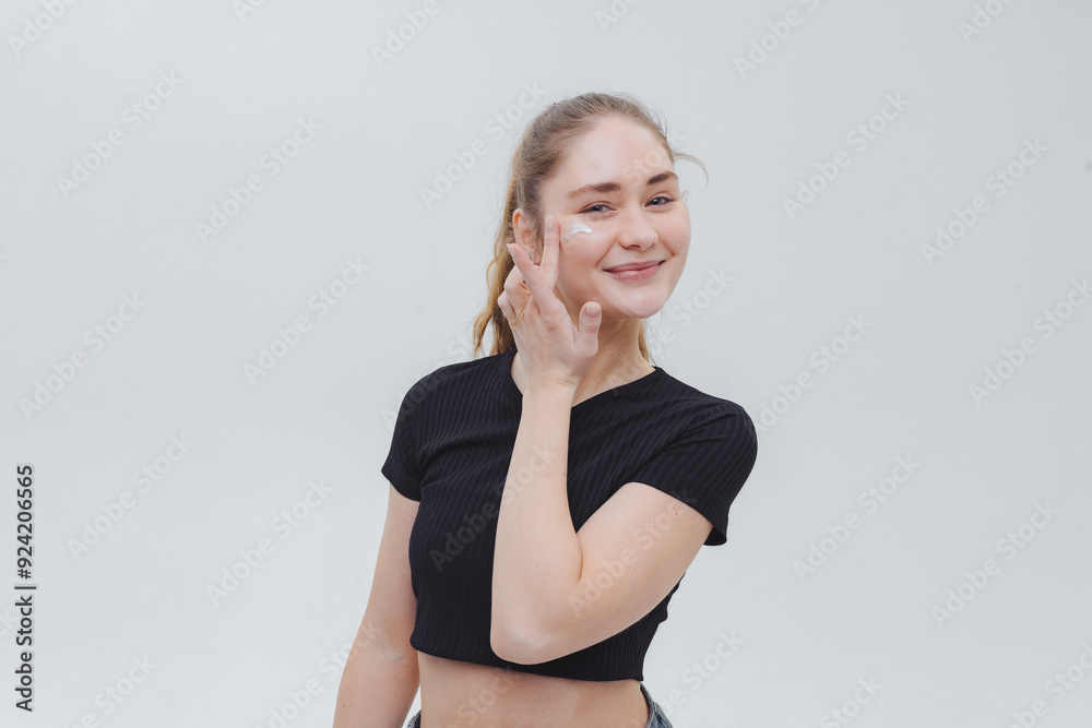 Young woman applying skincare in a bright minimalist studio on a sunny afternoon Young woman applying skincare in a bright minimalist studio on a sunny afternoon