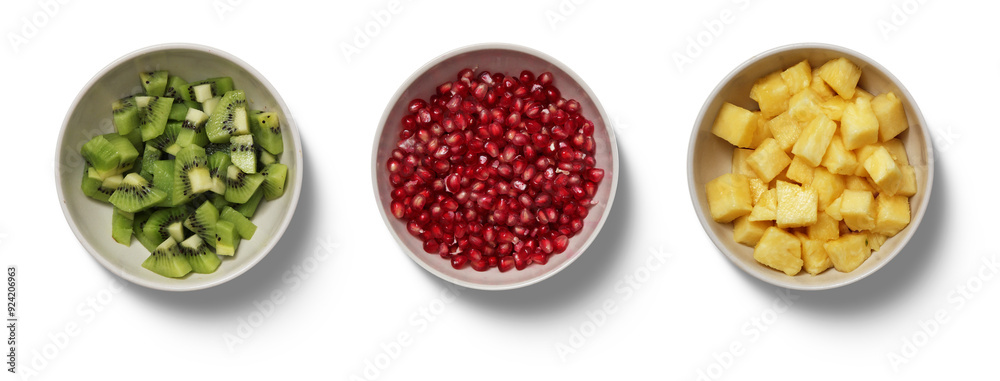 Naklejka premium Three bowls hold vibrant kiwi, pomegranate seeds, and pineapple chunks, showcasing a colorful selection of fresh fruits on a clean, white background