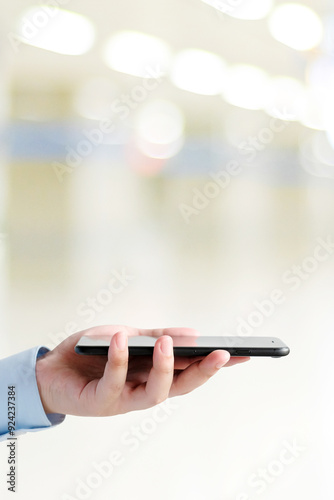 Man hand holding black smart phone over blur background with copy space, template, technology and lifestyle