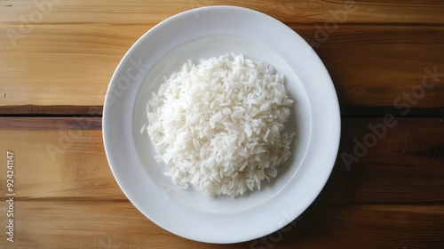 A portion of steamed Thai Jasmine rice on a white plate, viewed from above on a wooden table. Simple, aromatic, and ready to serve.