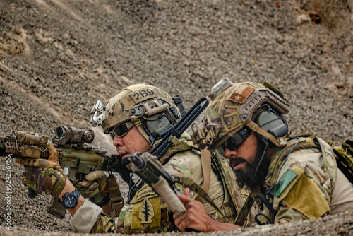 A group of military men in combat gear patrol in the middle of a desert and tropical jungle. Soldiers in full combat gear in dry weather conditions assemble and march on a mission.