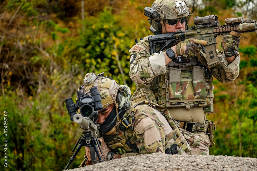 Fototapeta premium A group of military men in combat gear patrol in the middle of a desert and tropical jungle. Soldiers in full combat gear in dry weather conditions assemble and march on a mission.